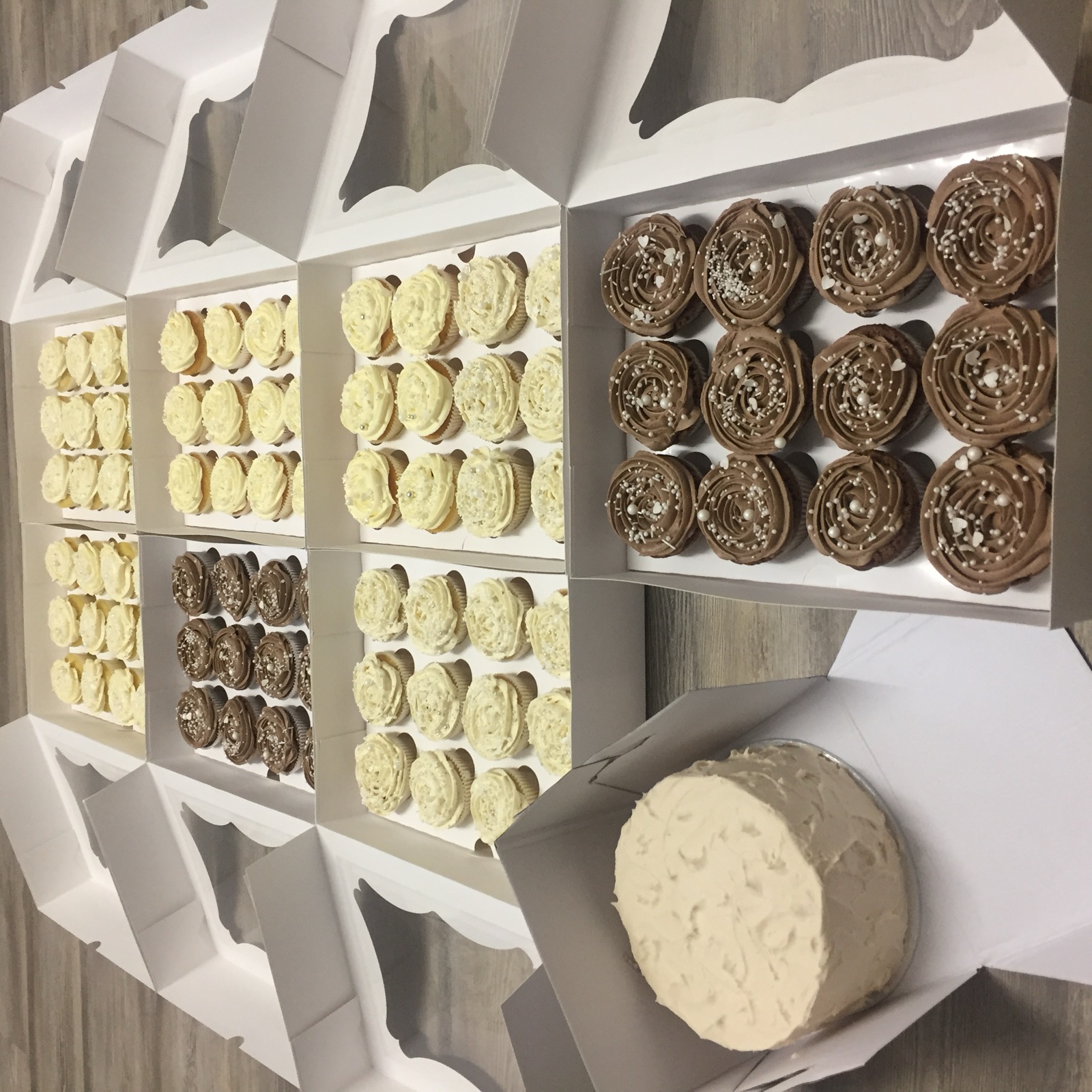 Schlichte helle Rundtorte neben Cupcake-Boxen